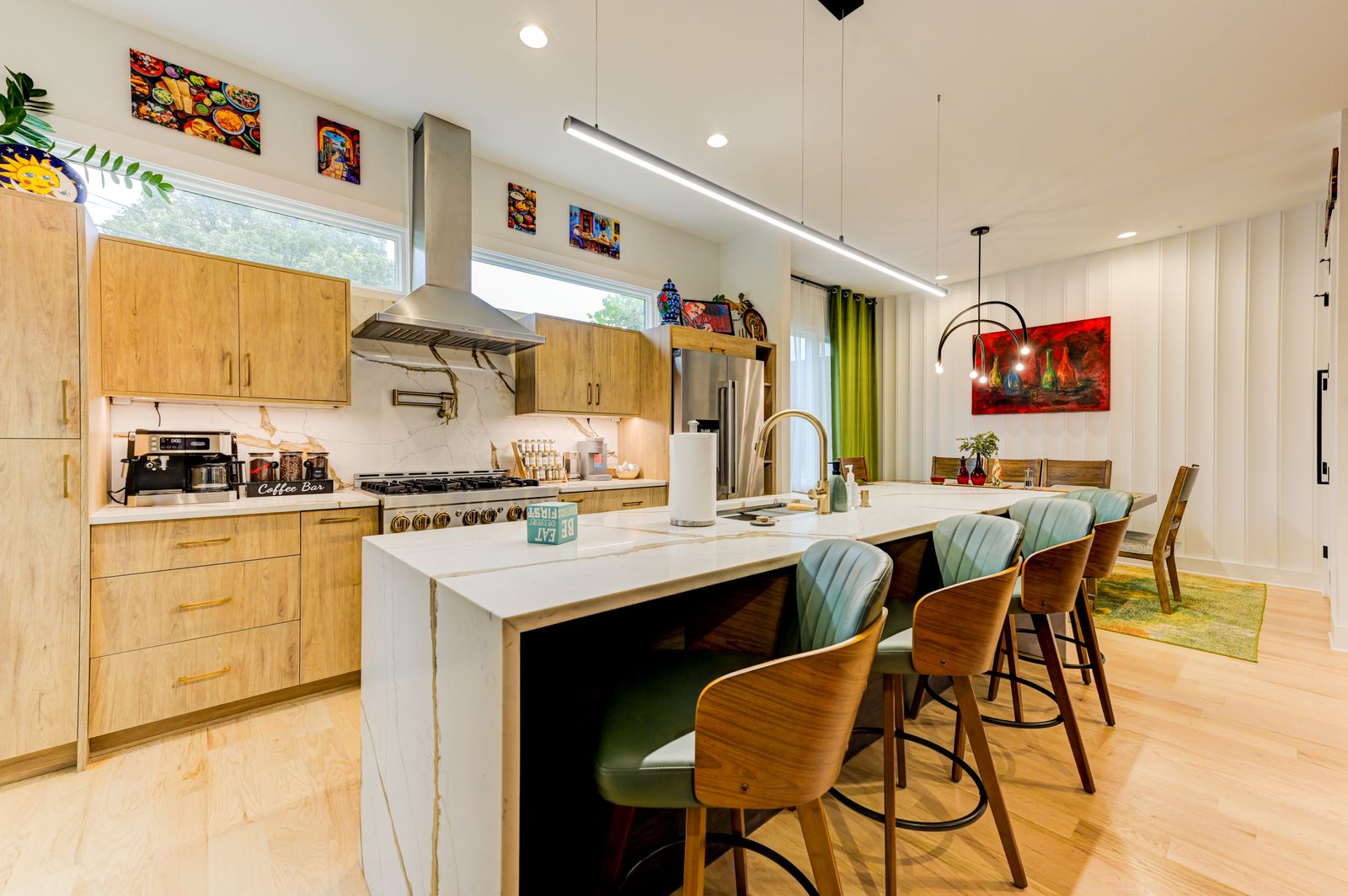 Open chef's kitchen with a marble waterfall island, custom oak cabinetry, and an adjoining dining and entertaining space