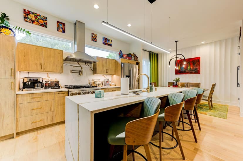Open chef's kitchen with a marble waterfall island, custom oak cabinetry, and an adjoining dining and entertaining space