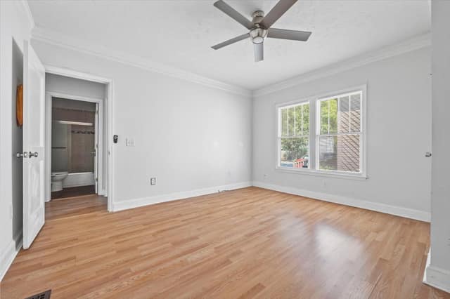 Bedroom with hardwood flooring, ceiling fan, and an adjoining bathroom