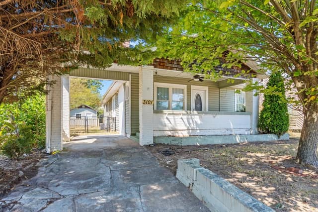 Covered front porch and private driveway with parking beside the home