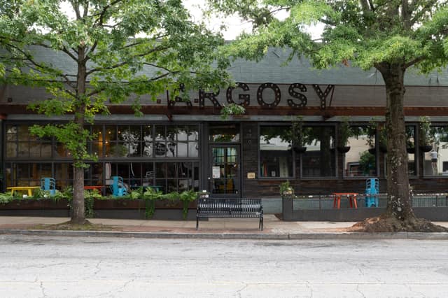 The Argosy in East Atlanta Village with sidewalk seating beneath mature oaks