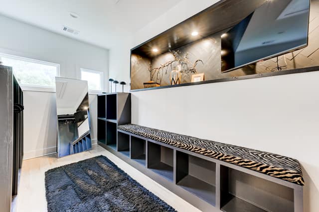 Custom dressing room with built-in bench seating and illuminated display niche