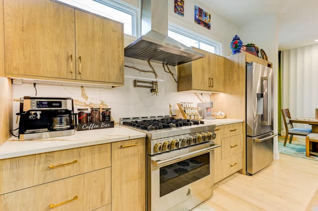Kitchen with JennAir gas range, marble-look backsplash, pot filler, and white oak cabinetry