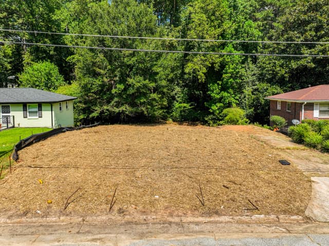 Front view of the vacant lot with trees in the background