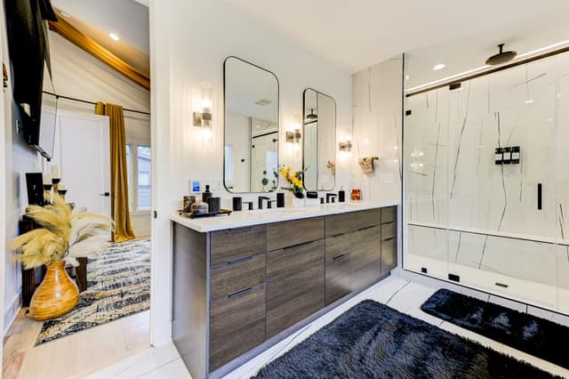 Primary bath with double vanity, backlit mirrors, and marble-look porcelain