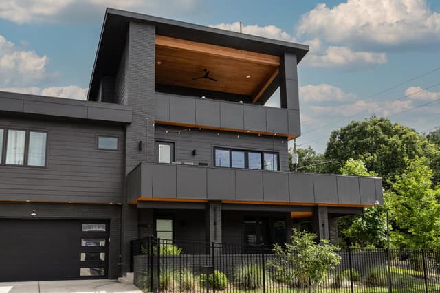 Front elevation of the residence with cedar-clad upper terrace and matte black facade