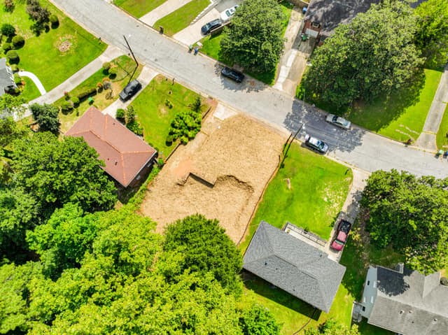 Aerial view of the vacant lot among neighboring homes and trees