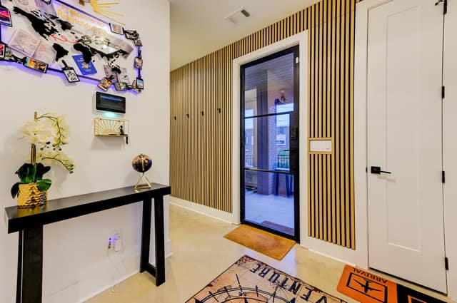 Entry foyer with fluted oak paneling, smart home panel, and glass front door