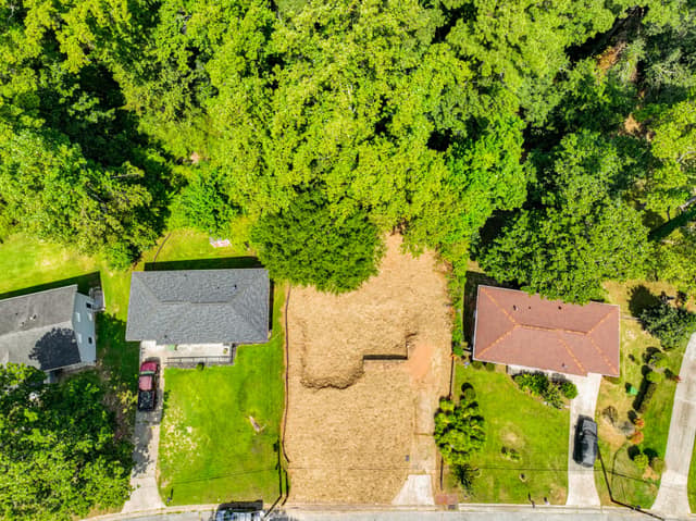 Overhead view of the vacant lot, nearby rooftops, and tree canopy