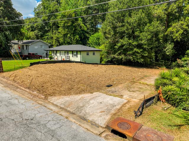 Street-level angled view of the vacant lot with neighboring homes and trees